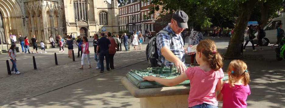 A father and his daughters are pictured engaging with a tactile map of York city centre