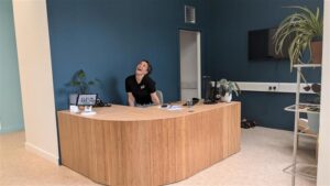 A young woman sitting behind a wooden reception desk.